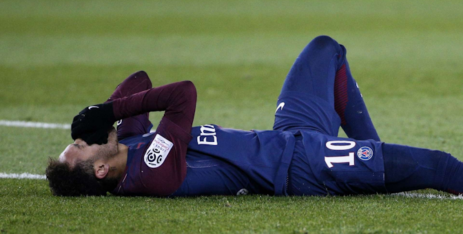 Footballer lying on the ground with hands over his face in disappointment