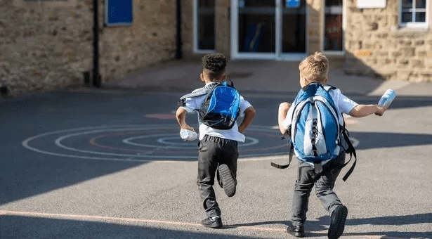 Small children running into school