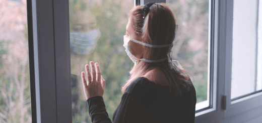 Girl in a covid mask staring out of the window